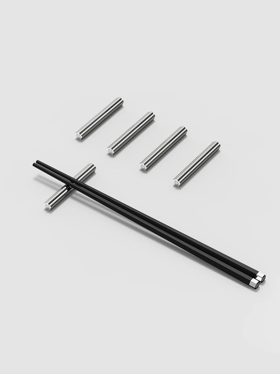 Minimal studio still life of full 5-piece LINGLONG chopstick rest set with black wood chopsticks on solid light grey backdrop