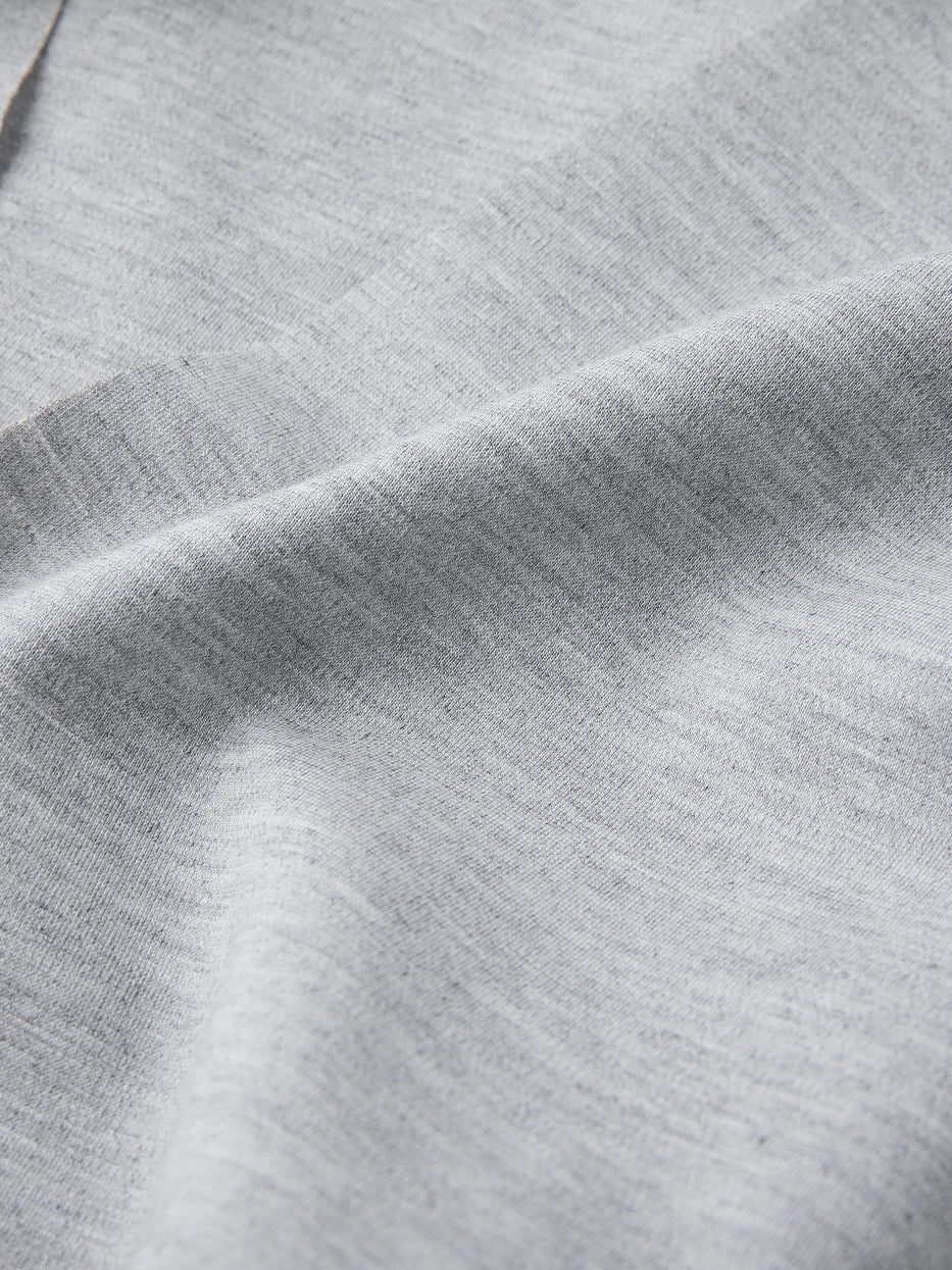Extreme macro texture close-up of MAYA stretch silk cotton bathrobe fabric, dense light heather gray mixed knit grain, clearly shows soft matte luster of silk cotton and high stretch rebound performance, lightweight single layer without stuffy thick texture