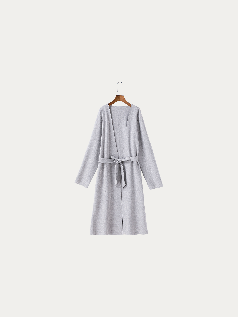 Official hanging product shot of MAYA light gray stretch silk cotton bathrobe size M on pure off-white background, solid light heather gray fine knit fabric, minimalist kimono V-collar, matching fabric wide waist tie, dual side patch pockets, all-in-one single-layer skin-friendly all-season home bathrobe