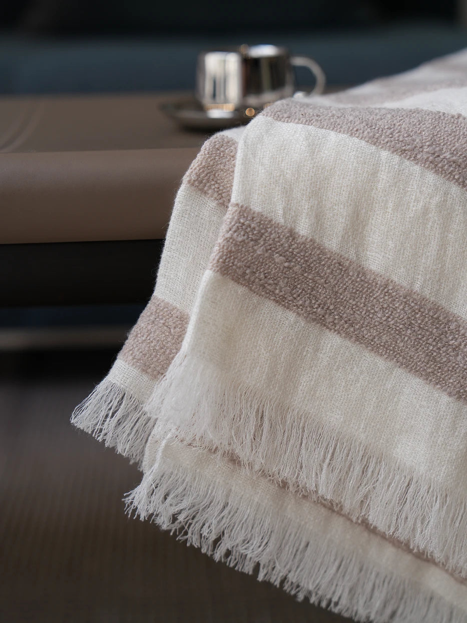 Extreme close-up texture shot of MUJIE linen wool blend throw blanket, showing bumpy woven beige stripe texture and loose handmade tassel fringe detail, visible breathable linen weave and soft wool mixed touch, neatly cut natural fringed edges, displays premium multi-fabric craft and tactile texture for home textile product displa