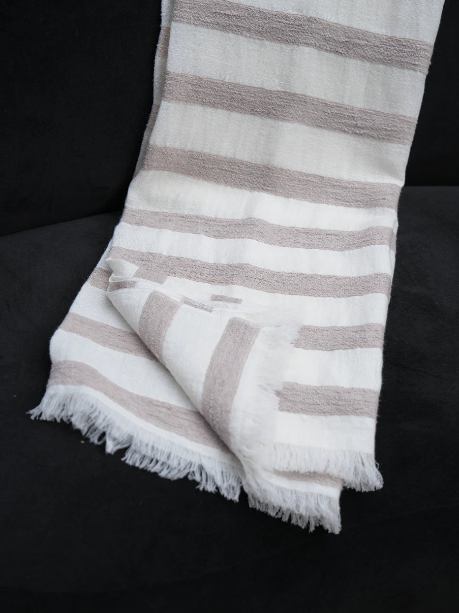 Minimalist interior still shot of MUJIE striped linen throw draped over curved black accent armchair on solid wood flooring, warm soft contrast between light beige textile and dark furniture, lightweight silky breathable fabric without bulky texture, great decor for entryway lounge, reading nook, hotel rest corner, modern dark tone interior matching