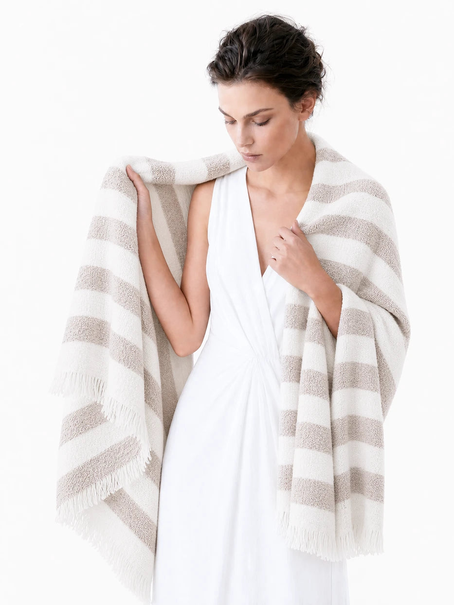 Pure white background half portrait shot of model wrapped with MUJIE khaki striped linen blanket, demonstrates multi-scene usage as wearable shawl, office nap cover, outdoor beach wrap, lightweight breathable linen wool blend fabric suitable for all seasons, minimalist wearable home textile for daily rest and travel
