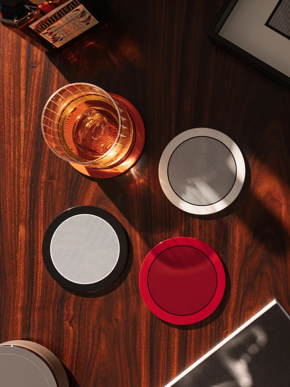 RESONG OPTICAL ART Round Coaster Collection featuring handcrafted lacquer coasters in multiple colors with geometric Op Art patterns, designed for luxury whisky serving, coffee table styling and contemporary home interiors.