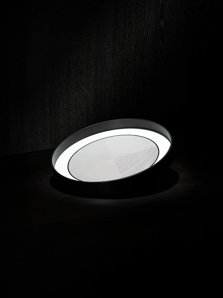 Minimalist texture close-up shot of empty black medium round tray on dark natural wood grain surface, side light highlighting glossy lacquer and inner geometric texture