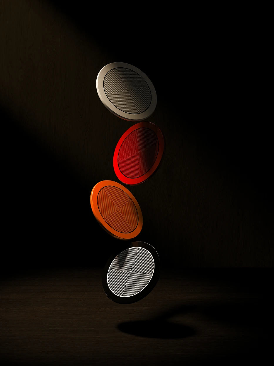 Art texture still life shot of full set multi-color round coasters suspended in layers against dark wood grain background, side light highlighting glossy lacquer and inner geometric texture
