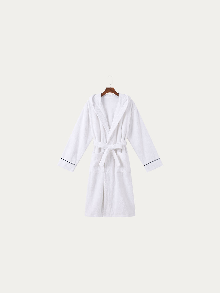 Official hanging product shot of R Collection white hooded bathrobe with navy piping on pure off-white background, 100% thick high-density cotton terry fabric, integrated three-dimensional hood, kimono V-collar, matching fabric wide waist tie, dual large side patch pockets, thin navy contrast piping on cuffs, 120cm long premium water-absorbent bathrobe for hotel and homestay use