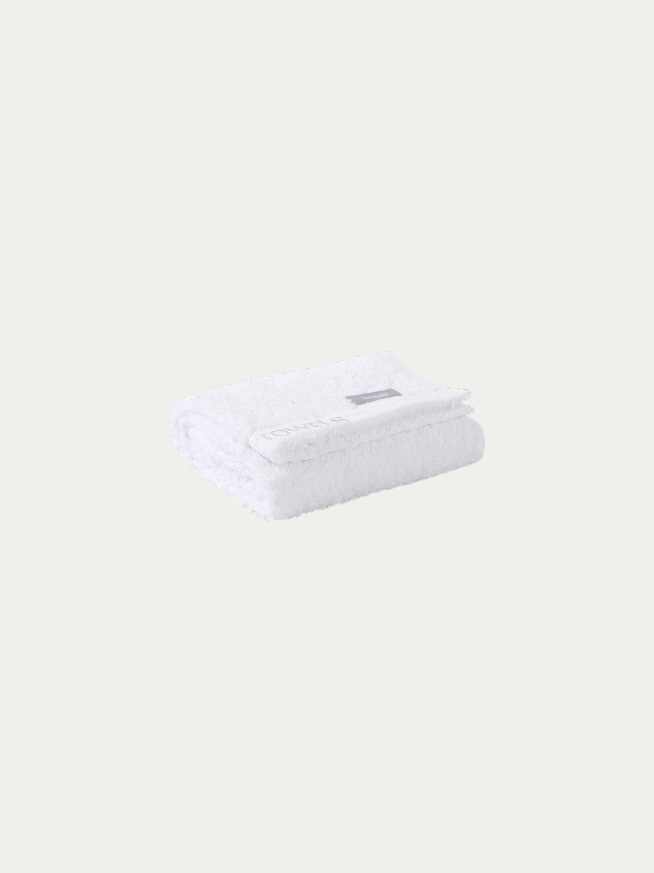 Official folded product shot of R Collection white cotton face towel on pure off-white background, oversized 750×410mm, 195g heavyweight thick terry, woven band embroidered with TOWELS logo, water-absorbent facial towel for hotel & gift box matching