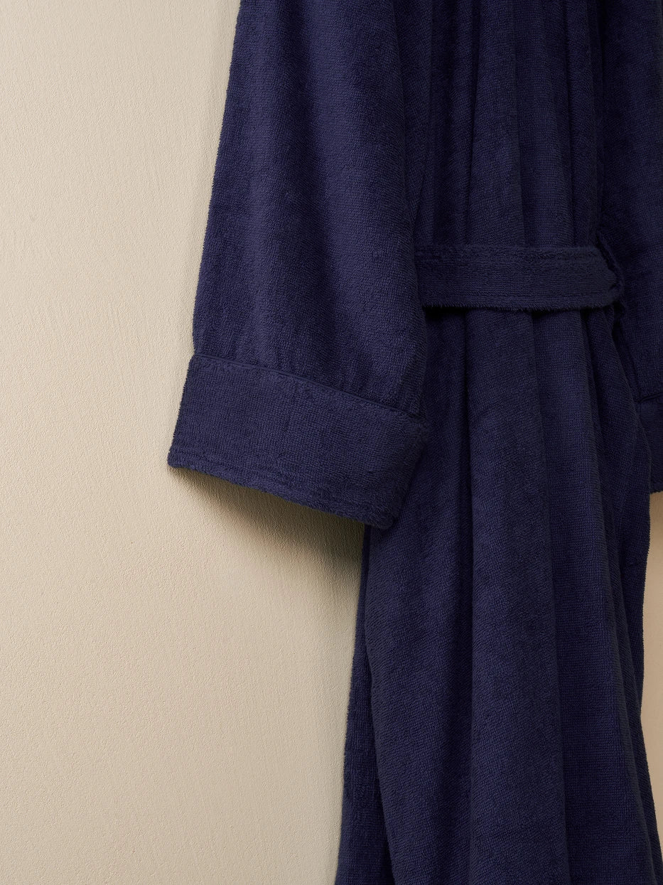 Macro close-up of folded double-layer wrapped cuff edge of R Series navy blue cotton bathrobe, uniform neat same-color cotton lock stitching, double-layer fitted terry fabric, displays precise wash-resistant sewing craft that prevents loose threads
