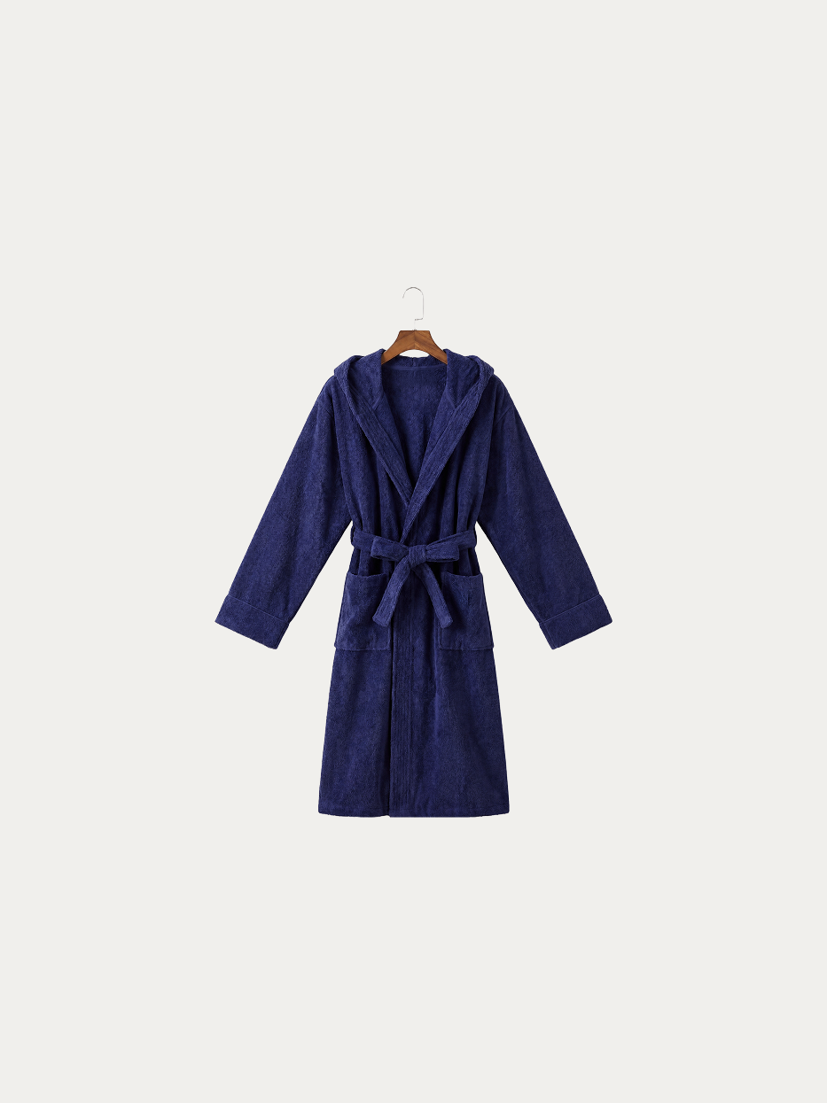Official hanging product shot of R Series navy blue hooded bathrobe on pure off-white background, 100% thick high-density cotton terry fabric, integrated three-dimensional hood, kimono V-collar, matching fabric wide waist tie, dual large side patch pockets, 120cm long water-absorbent bathrobe for home, hotel and spa use
