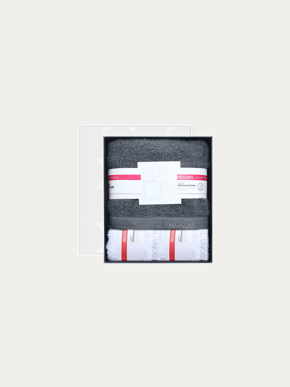Official window gift box shot of R Series mixed set (2 white face towels + 1 grey bath towel) on pure off-white background, includes 2 white face towels & 1 full-size grey bath towel, 100% long-staple cotton heavy dense terry, minimalist red-white brand waist band, unisex premium business bathroom gift set