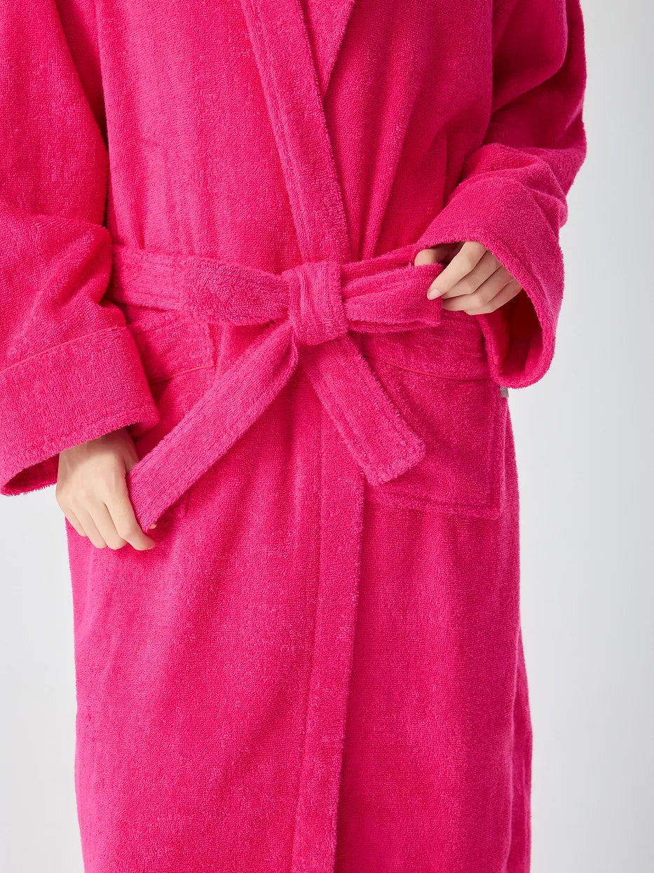 Close-up of RESONG rose red hooded terry cloth bathrobe showing matching belt tie bow, patch pockets and wrap front, hands holding belt ends, soft absorbent cotton texture, white background

