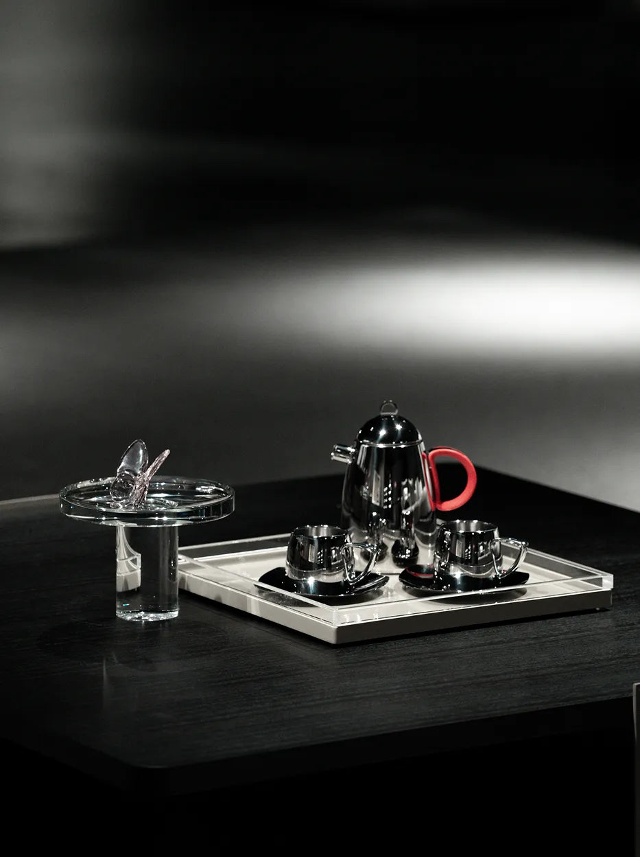Official lifestyle image of the RESONG SHEDI Red Handle Teapot - S, a mirror-polished stainless steel teapot with matching cups styled on a contemporary tea table for elegant home entertaining.
