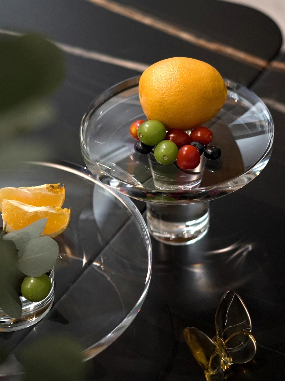 Luxury commercial display shot of large SHIJI L fruit plate full of pineapples & fruits, matched with M plate of avocados and lemons on matte dark stone bar counter