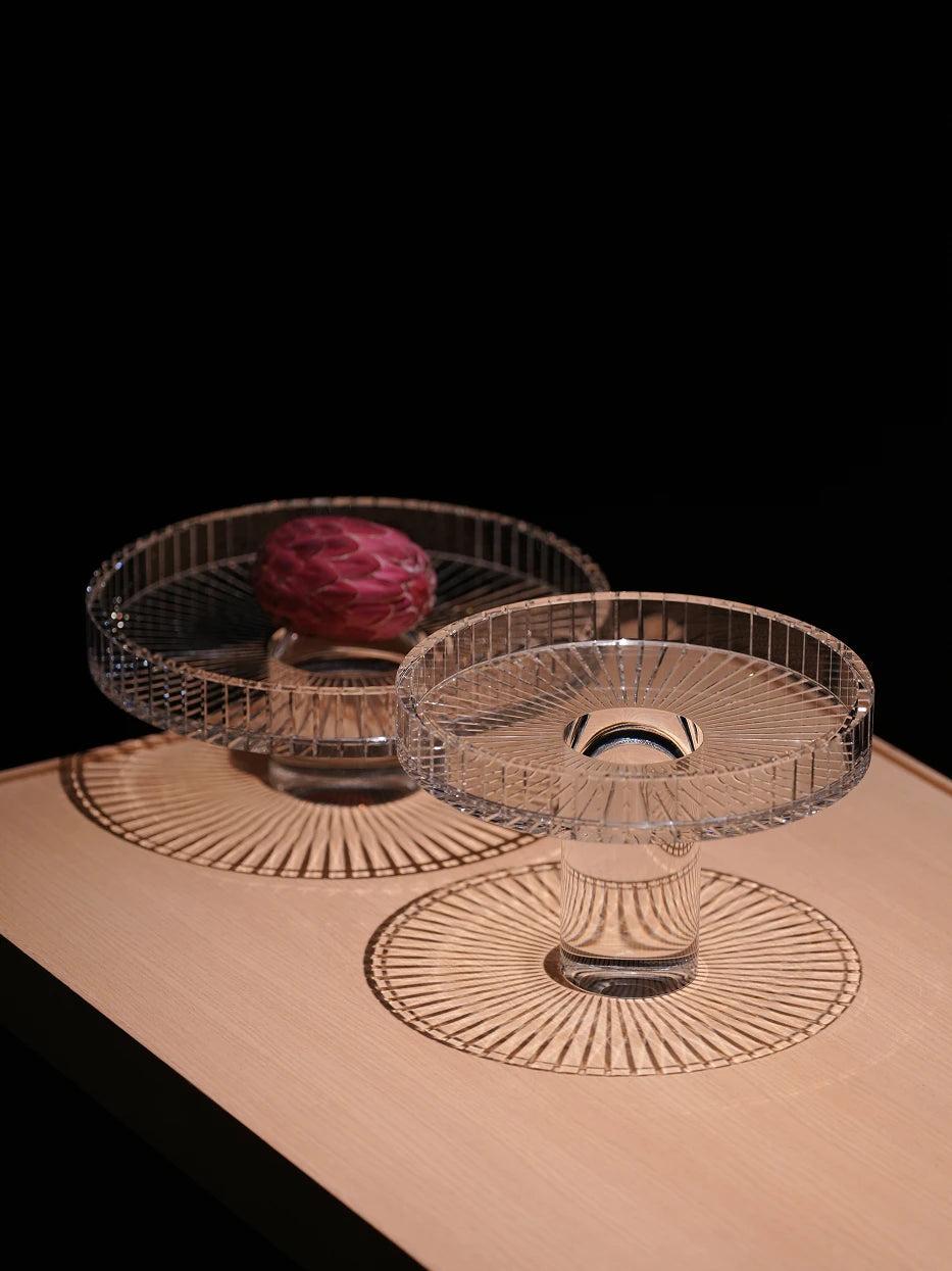 Home soft furnishing layout shot of SHIJI L & M crystal fruit plates on light log tabletop with decorative flower, transparent glass casting neat radial light shadow