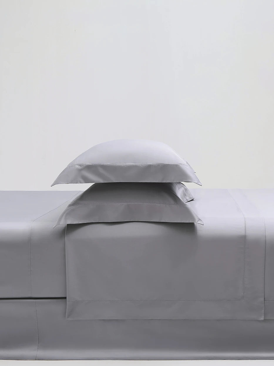 Close-up furnishing shot of full SHUMIAN gray bedding pillow set showing silky Awat cotton fabric & fine double-line eyelet embroidery edge
