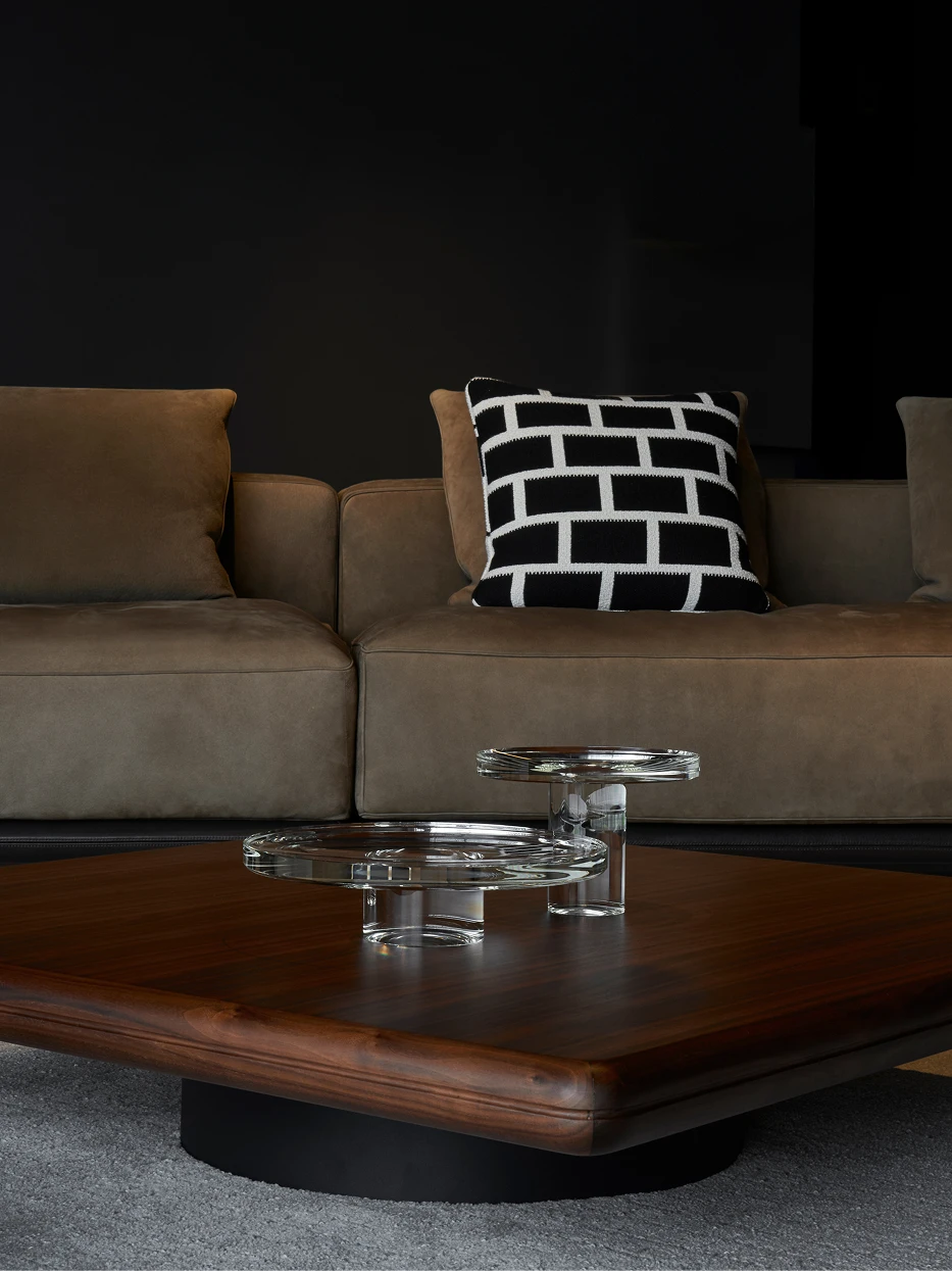 Modern living room layout shot of staggered STARLIGHT L & M crystal fruit plates on dark walnut square coffee table with fabric sofa backdrop