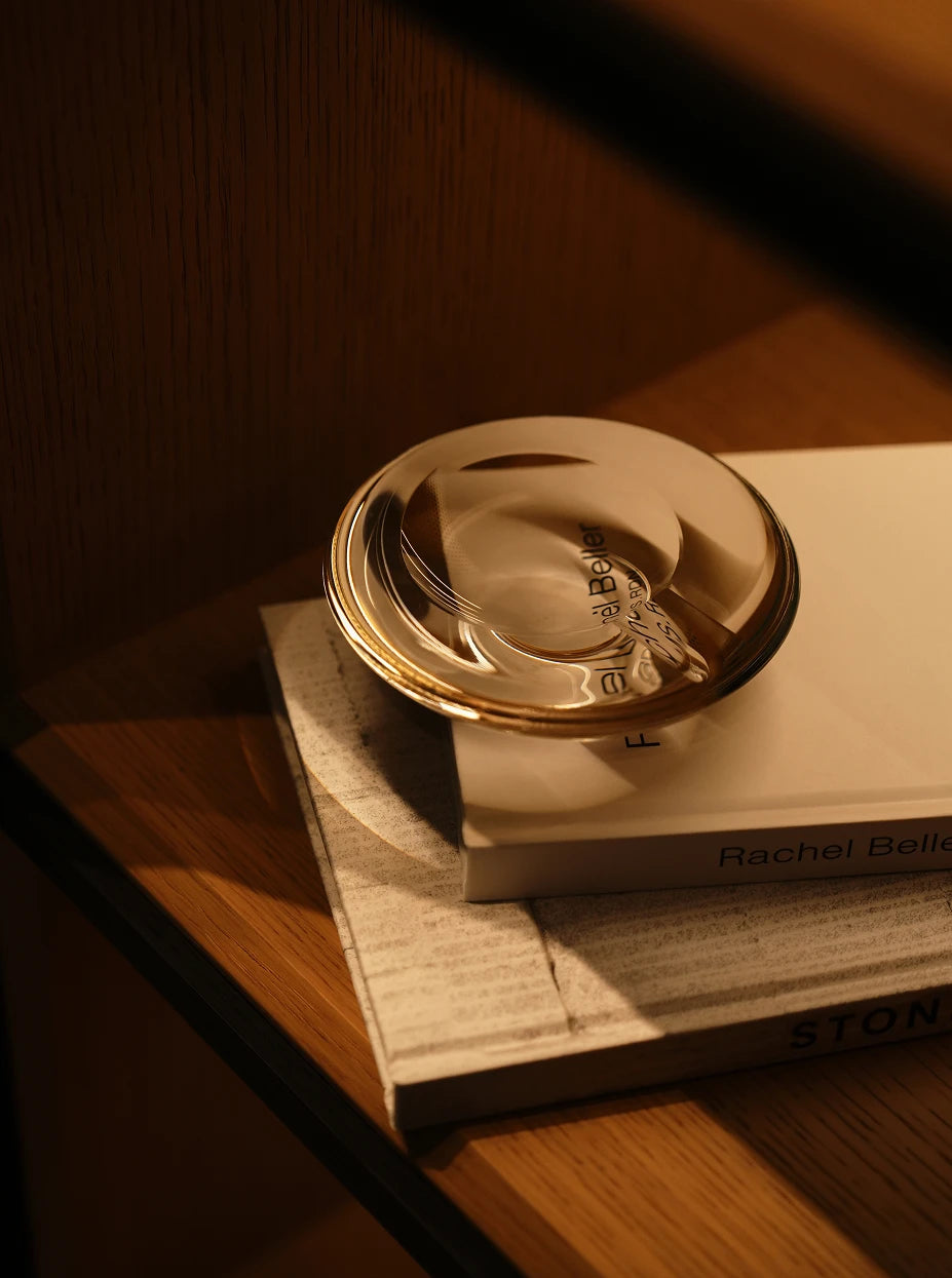Warm tone furnishing shot of WATERDROP M crystal ashtray stacked on hardcover art books on wood side table