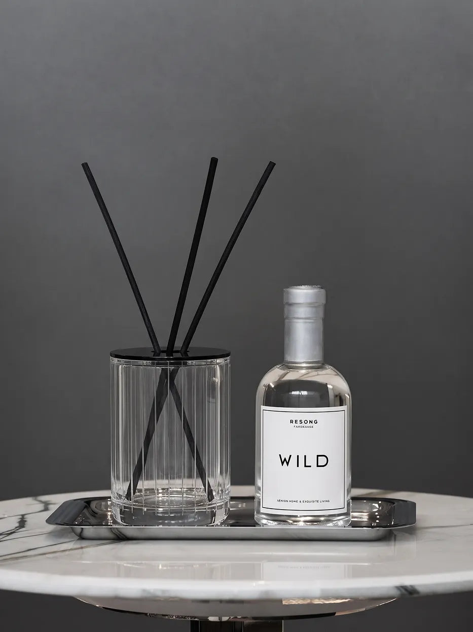 Monochrome minimalist living furnishing shot of WILD aromatherapy bottle matched with XUYU striped crystal diffuser on white-vein marble rou