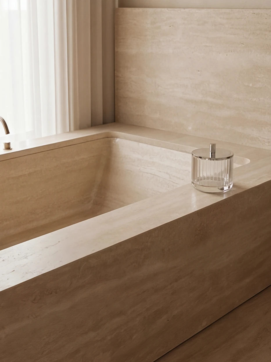 Cream minimalist bathroom furnishing shot of XUYU crystal storage box beside freestanding travertine bathtub
