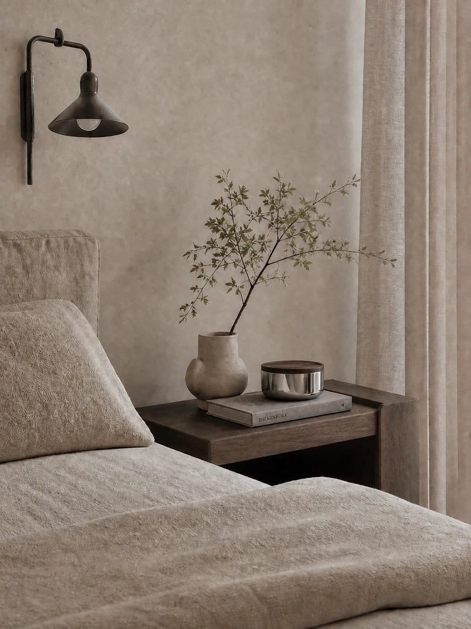 Warm log-style bedroom layout shot of YINGMU L storage can laid on walnut nightstand with fabric bedding and foliage vase